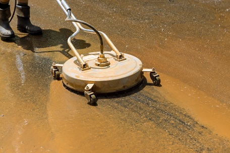 A high pressure cleaner cleaning a dirty driveway
